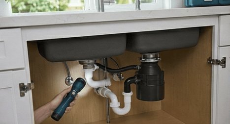 Garbage Disposal and Kitchen Plumbing Repair Plumber repairing garbage disposal and kitchen drain plumbing under a sink